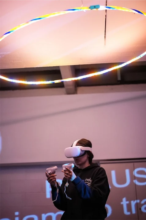 Young student interacts with virtual reality using a visor and two controllers